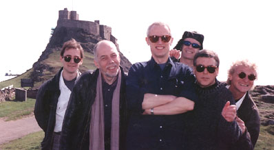 picture of the final lineup of Lindisfarne the group all smiling on Lindisfane island with the castle in the background